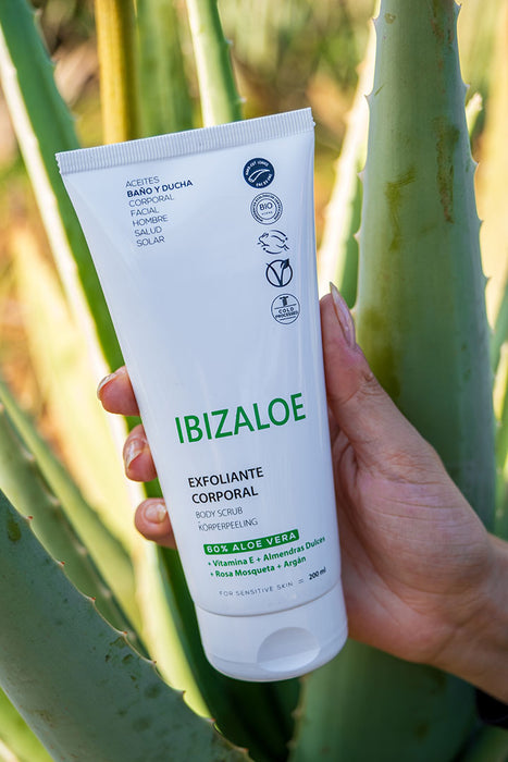 "Aloe Vera Körperpeeling" in Tube aus Kunststoff vor einer Aloe Vera Pflanze.